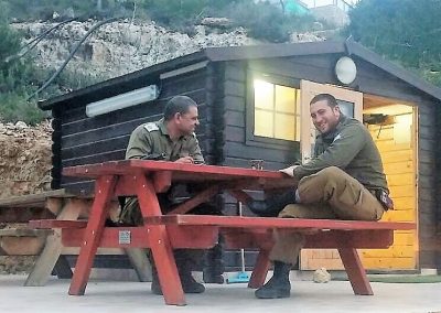 Two soldiers enjoying a break outside a wooden Warm Corner in Ateret