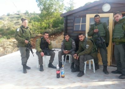 A group of soldiers sitting and enjoying a cool beverage outside a wooden Warm Corner in Ateret